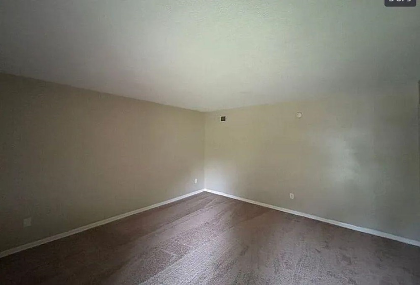 Empty room featuring dark carpet and baseboards