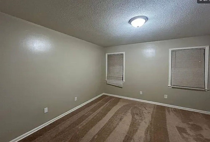 Unfurnished room featuring a textured ceiling and dark colored carpet