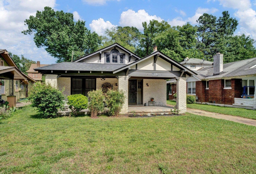 View of front of house featuring covered porch, a front yard, and brick siding