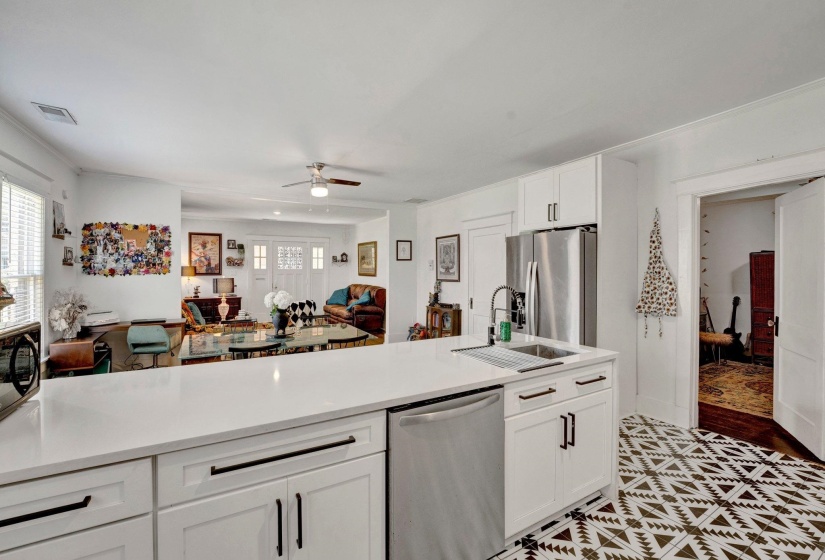 Kitchen featuring white cabinetry, stainless steel appliances, open floor plan, a ceiling fan, and light stone counters