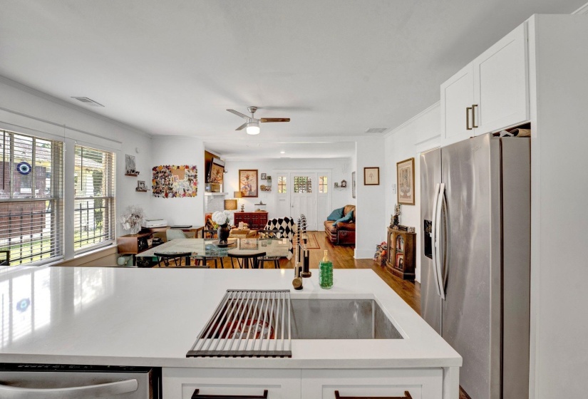 Kitchen featuring white cabinetry, open floor plan, stainless steel appliances, a ceiling fan, and crown molding