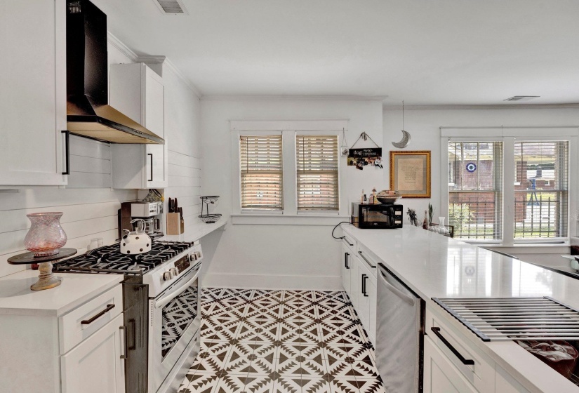 Kitchen featuring white cabinetry, stainless steel appliances, light stone counters, decorative backsplash, and healthy amount of natural light