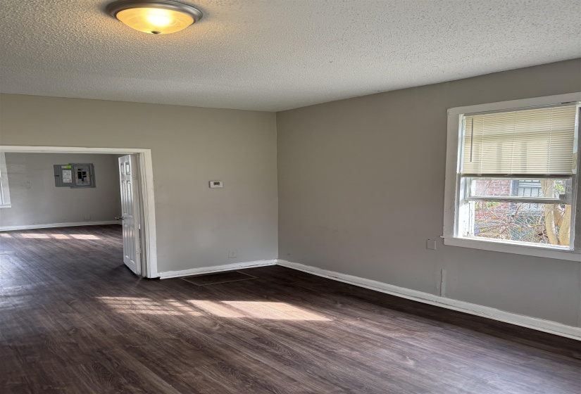 Unfurnished room with a textured ceiling, dark wood-style flooring, and electric panel
