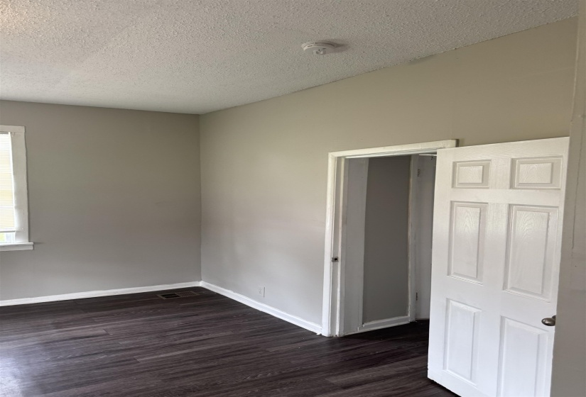 Empty room with dark wood-style floors and a textured ceiling
