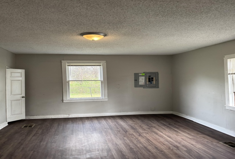Spare room featuring electric panel, dark wood-type flooring, and a textured ceiling