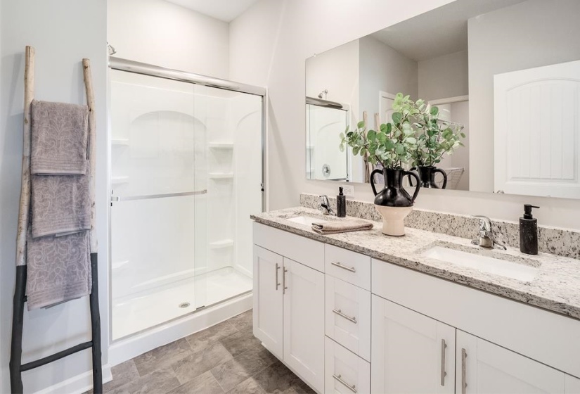 Full bathroom featuring double vanity and a stall shower