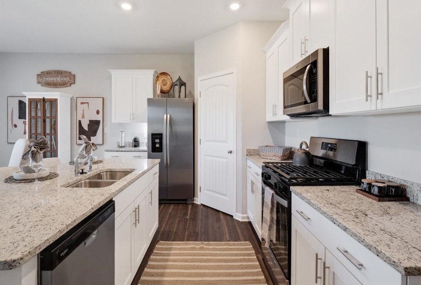 Kitchen featuring stainless steel appliances, white cabinetry, and light stone counters