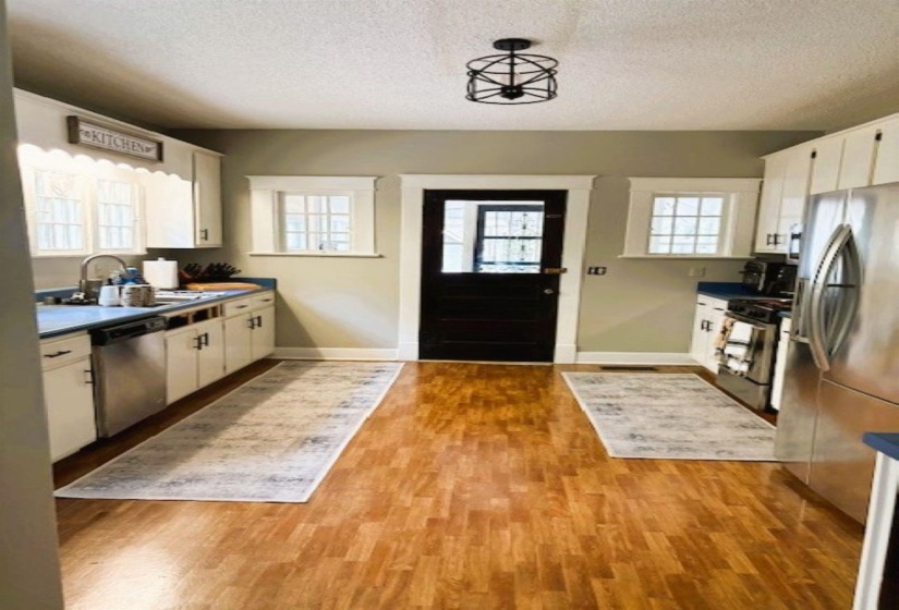 Kitchen featuring white cabinetry, stainless steel appliances, a textured ceiling, light wood-type flooring, and dark countertops