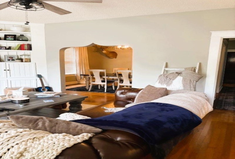 Living area featuring a textured ceiling, hardwood / wood-style flooring, arched walkways, built in features, and ceiling fan