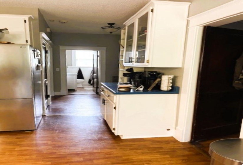 Kitchen featuring glass insert cabinets, freestanding refrigerator, dark wood finished floors, white cabinets, and a textured ceiling