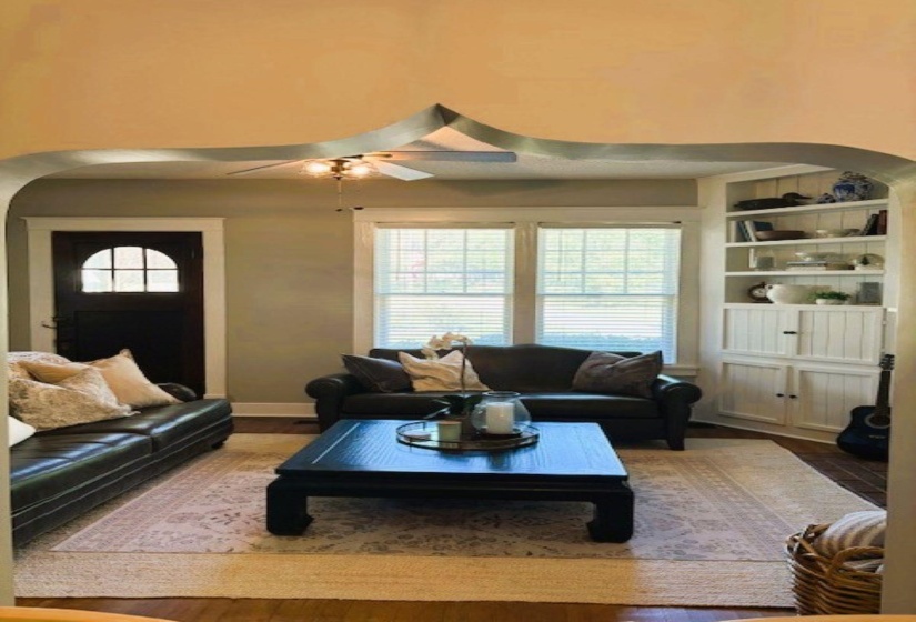Living room featuring arched walkways, wood finished floors, and ceiling fan