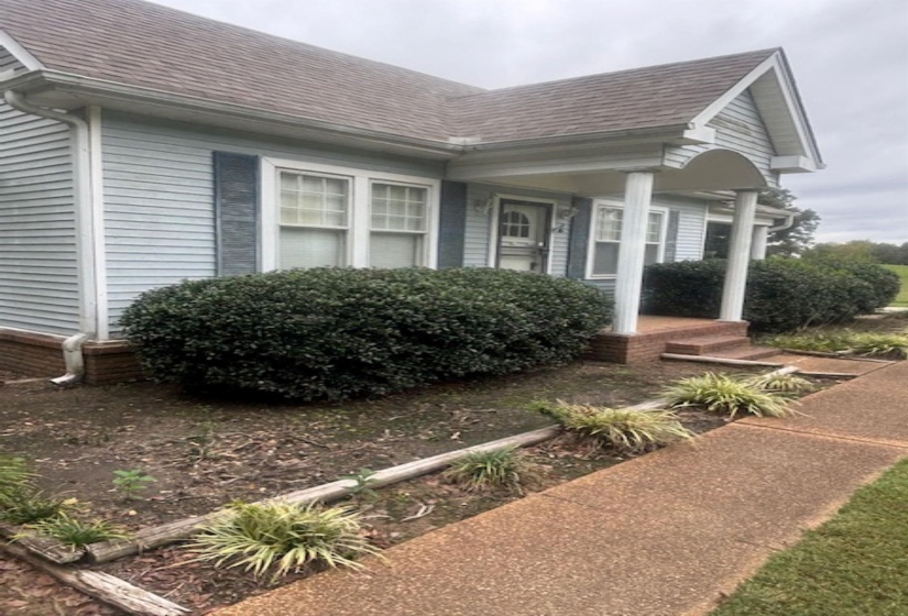 View of side of property with a shingled roof and a porch