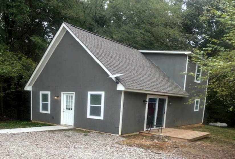 View of front of home featuring a shingled roof and a deck