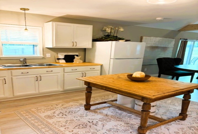 Kitchen featuring white cabinets, freestanding refrigerator, light countertops, and light wood-type flooring