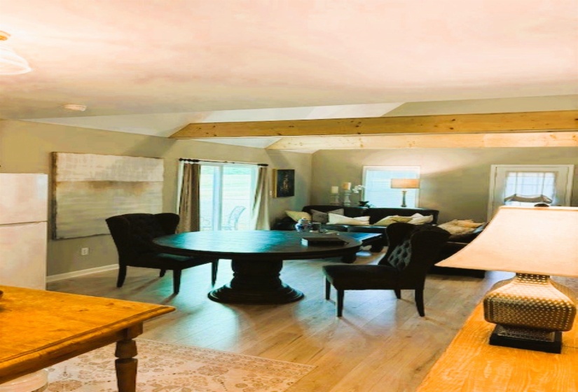 Dining space with light wood-style flooring and lofted ceiling with beams