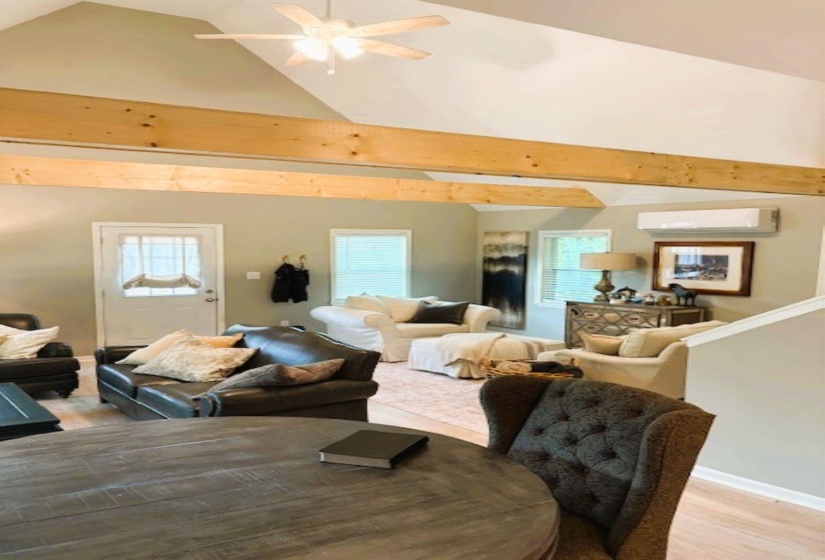 Living room featuring a ceiling fan, light wood finished floors, a high ceiling, and healthy amount of natural light