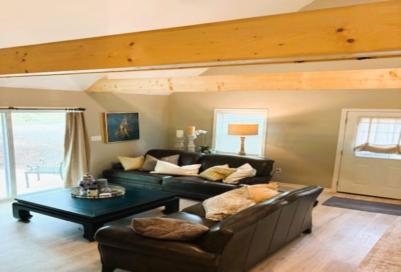 Living area featuring light wood-type flooring and vaulted ceiling with beams