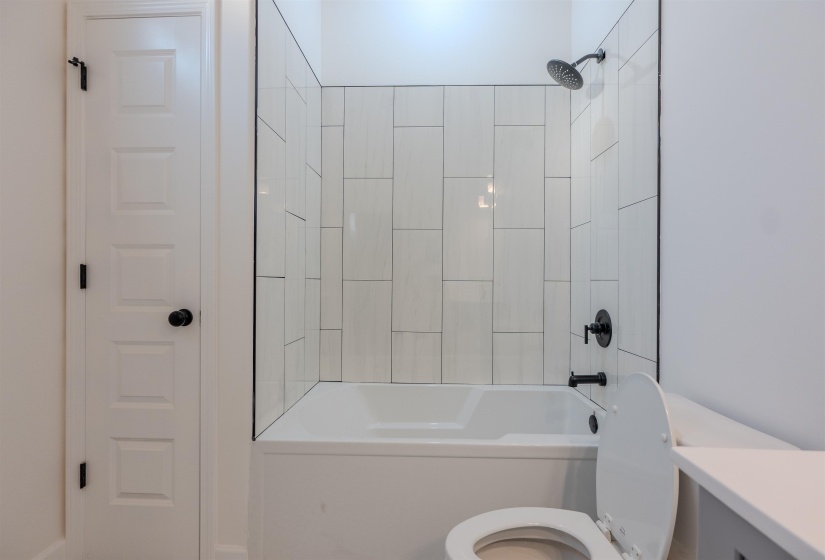 Full bathroom featuring tiled shower / bath combo, vanity, and toilet
