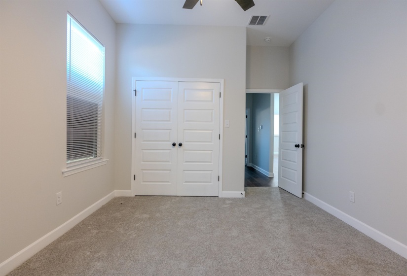 Unfurnished bedroom with ceiling fan, a closet, and light colored carpet