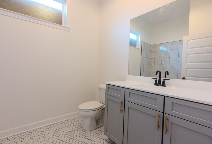 Bathroom featuring toilet, vanity, and a tile shower