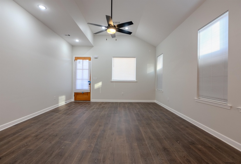 Spare room with ceiling fan, lofted ceiling, and dark wood-type flooring