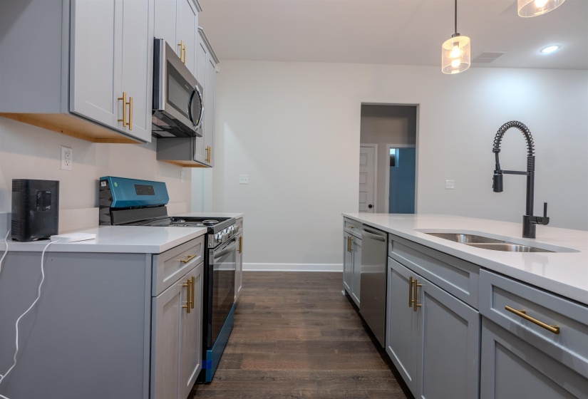 Kitchen with appliances with stainless steel finishes, sink, pendant lighting, and gray cabinetry