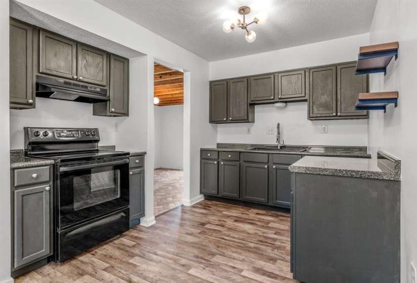Kitchen featuring black electric range oven, light wood finished floors, open shelves, a textured ceiling, and dark wood finish cabinets
