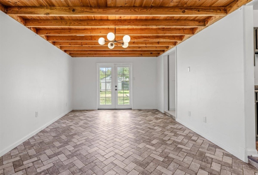 Below grade area featuring french doors, wooden ceiling, a chandelier, and brick patterned flooring
