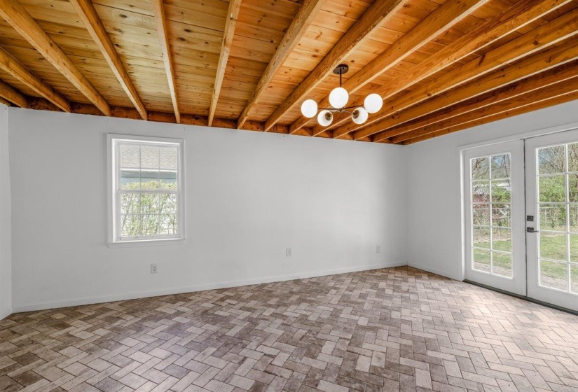Unfurnished room featuring french doors and a wooden ceiling with exposed beams