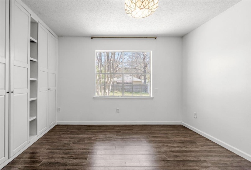 Unfurnished bedroom featuring dark wood-style floors, a textured ceiling, and a closet