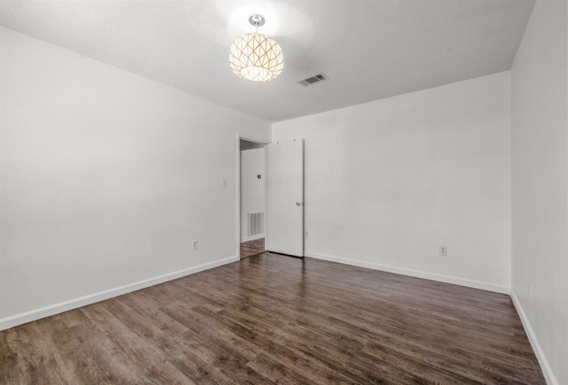 Unfurnished bedroom with dark wood-style flooring and a textured ceiling