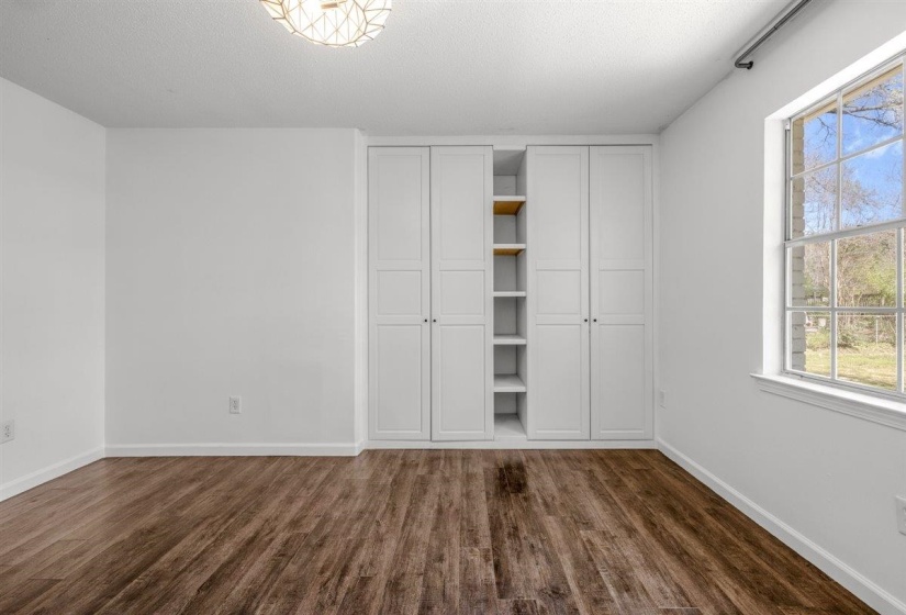 Unfurnished bedroom with a textured ceiling, dark wood finished floors, and two closets