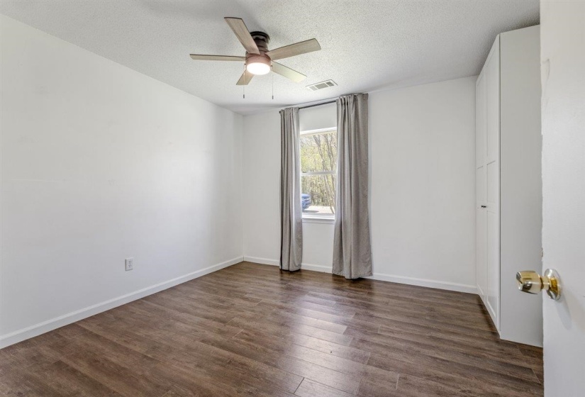 Empty room featuring dark wood-type flooring, a textured ceiling, and ceiling fan