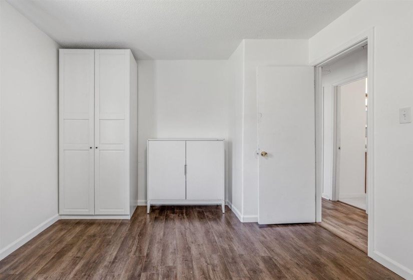Unfurnished bedroom featuring a textured ceiling, dark wood-style flooring, and a closet