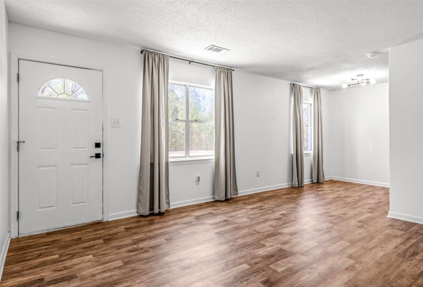 Entrance foyer featuring dark wood-style flooring, a textured ceiling, and healthy amount of natural light