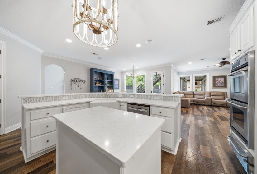Kitchen featuring white cabinetry, light-toned countertops, a central island, and stainless steel double ovens