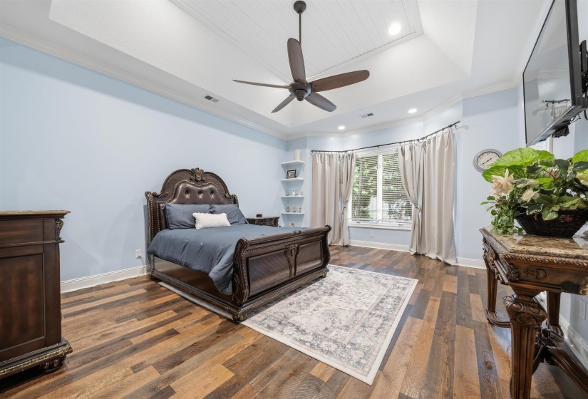 Spacious room featuring wood-finish flooring, a tray ceiling with wood paneling, and a contemporary ceiling fan