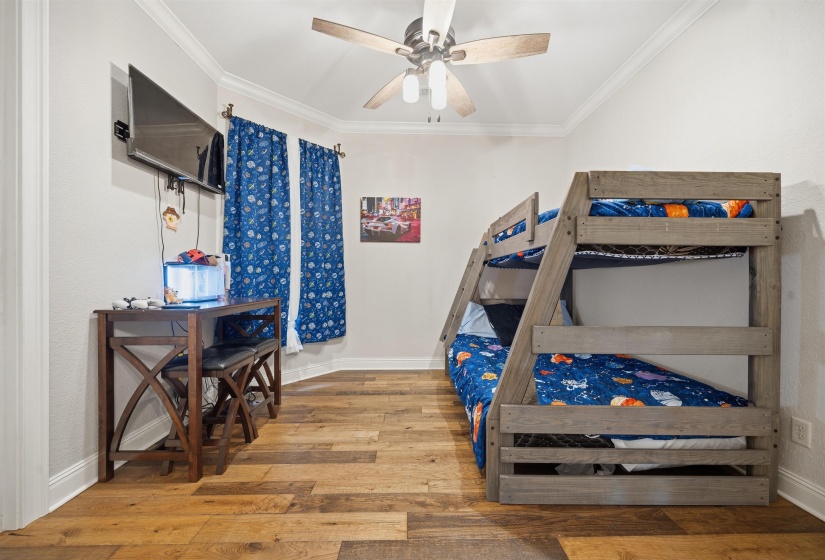 Interior room featuring wood-finish flooring, white walls, and a ceiling fan with integrated lighting