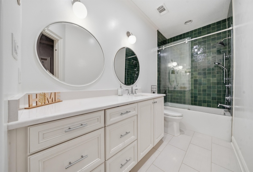 Dual circular mirrors above a double vanity with white cabinetry and a light-toned countertop