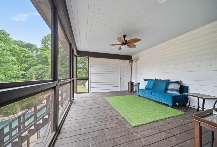 Spacious screened porch featuring dark wood-finish flooring, white shiplap walls, and a ceiling fan