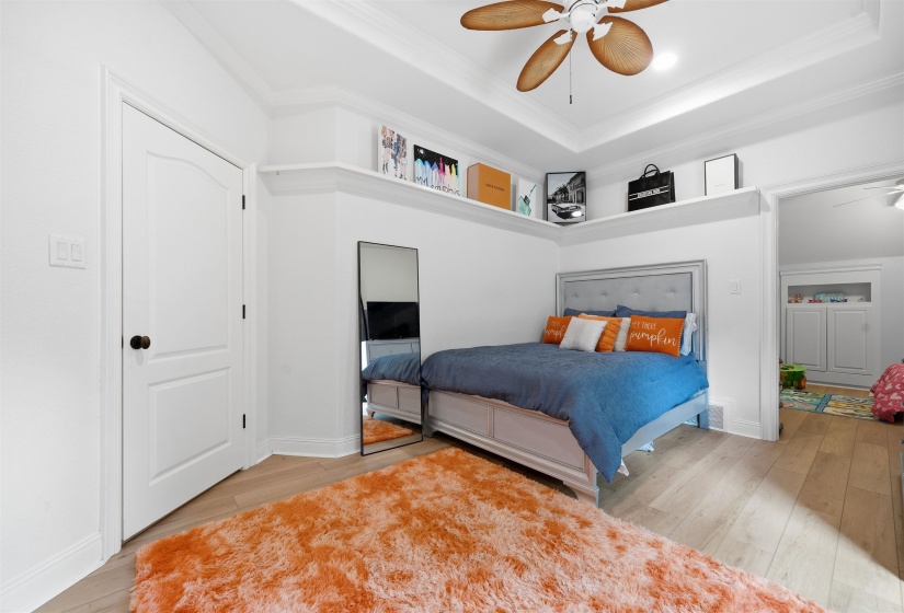 Spacious room featuring wood-finish flooring and a tray ceiling with a ceiling fan