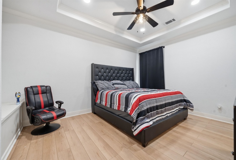 Bedroom featuring wood-finish flooring, a tray ceiling with recessed lighting, and a ceiling fan