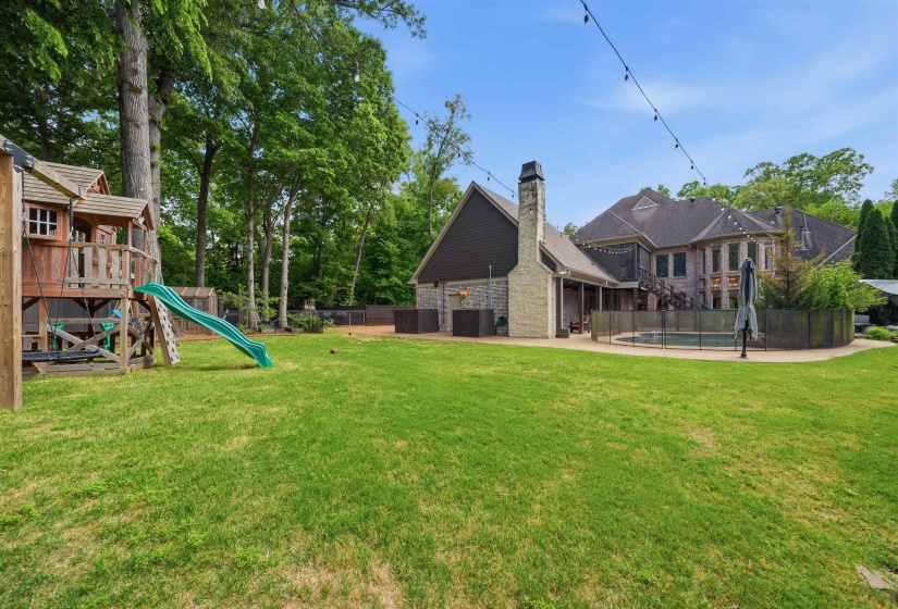Expansive green lawn with a wooden play structure featuring a slide