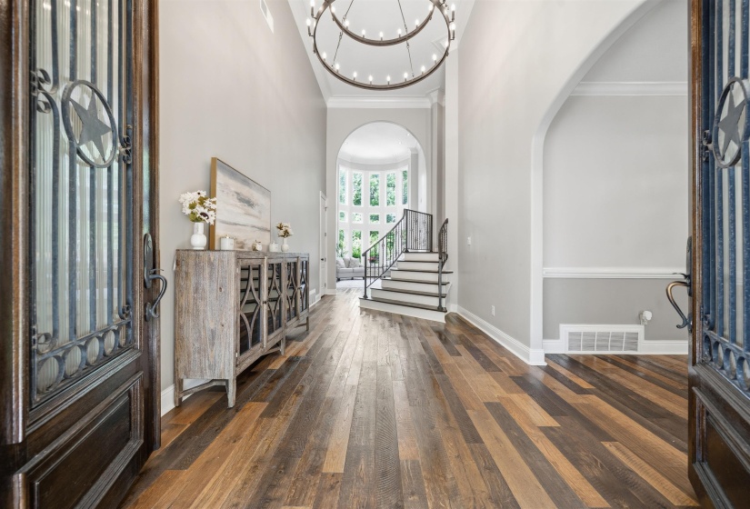 Grand entryway featuring multi-tone wood-finish flooring, a two-story ceiling, and an ornate chandelier