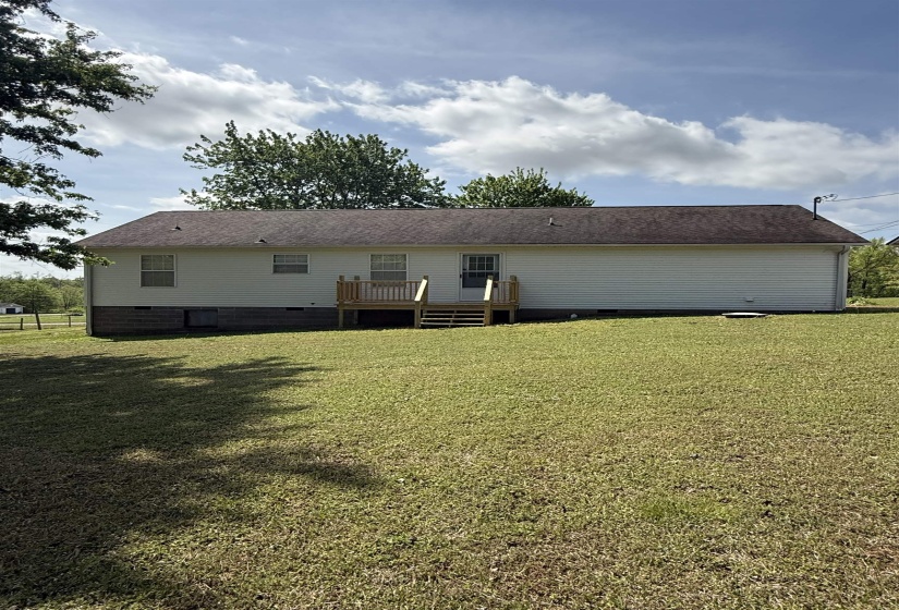 Back of property featuring crawl space, a deck, and a lawn