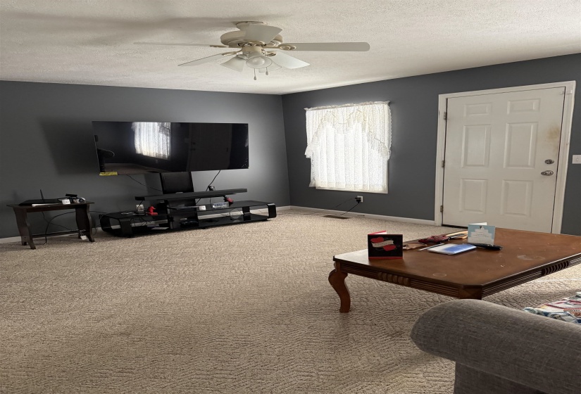 Carpeted living room featuring a textured ceiling and a ceiling fan