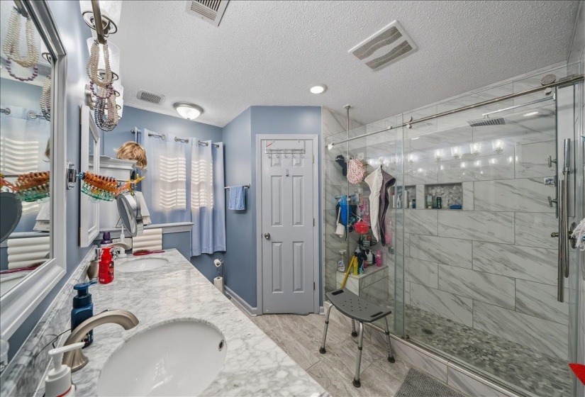 Bathroom featuring double vanity, wood tiled floors, a shower stall, and a textured ceiling