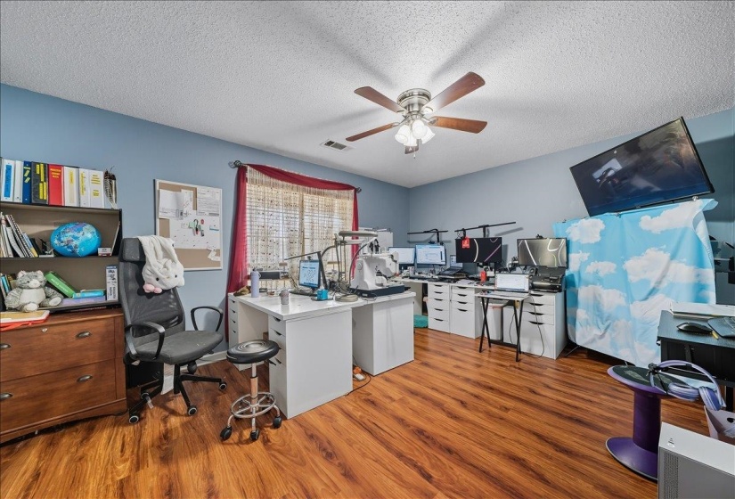 Office with light wood finished floors, a textured ceiling, and a ceiling fan