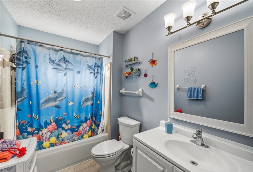 Bathroom featuring vanity, shower / tub combo with curtain, and a textured ceiling