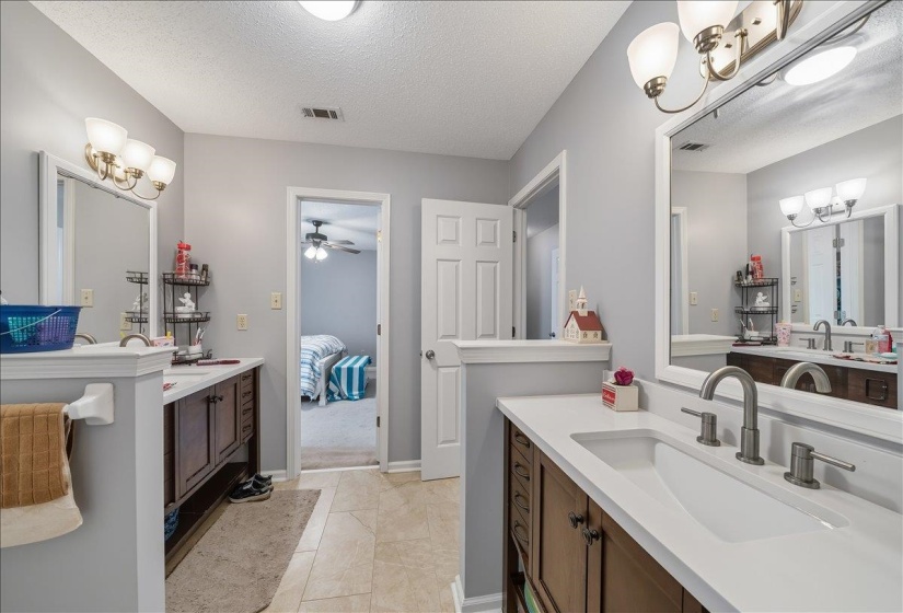 Ensuite bathroom featuring two vanities, a textured ceiling, ceiling fan, and hanging lights